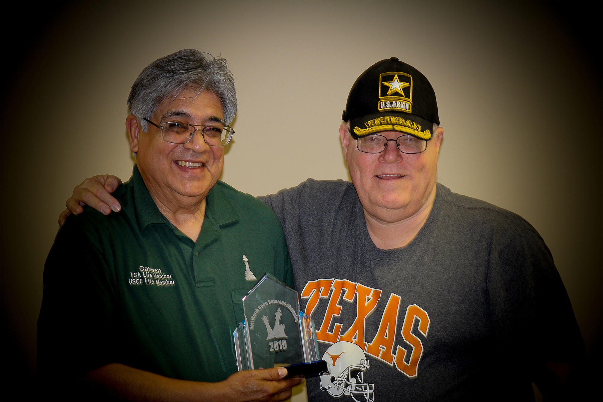 In March, Carmen Chairez (left) won his second straight Fort Worth Open Veterans Chess Championship.  In all the excitement both he and Troy Gillispie, the 2019 Fort Worth Veterans Chess Champion, went home with each other's trophy.  Jim Hollingsworth (right) was Chief TD of that event, too.  RRSO XVII was a great opportunity to exchange and marry the right trophy up with the right Veteran.  Photo by Sheryl McBroom.